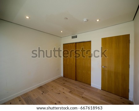Empty small bedroom modern style interior with wood floor wood built-in closet wood door white paint and encase lights