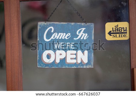 Business sign say "Come in now we open shop" in english & Thai language on the windows