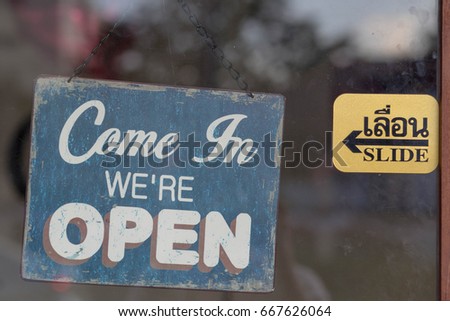 Business sign say "Come in now we open shop" in english & Thai language on the windows
