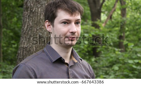 portrait of young businessman in forest, trees in the background.