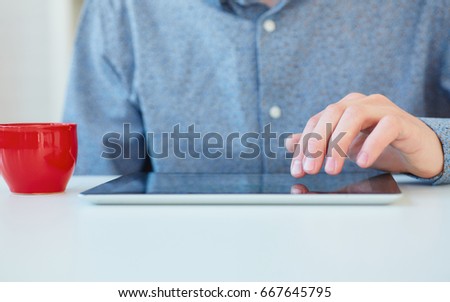 Man presses on the blank screen tablet computer. Concept: man working from home using tablet computer. Free space for text. 