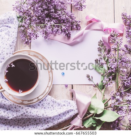 Morning cup of tee, cookies, and lilac flower on wooden table from above. Beautiful breakfast. Flat lay style with copy space