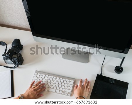 Woman working a video editing project on a modern computer setup with black screen
