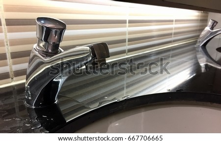 Faucet in sink with water leaking. Royalty-Free Stock Photo #667706665