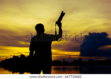 silhouette of a photographer who shoots a sunset in the river
