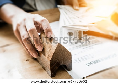 Young business man giving house  of customer  and holding dollar us bank at  agency office. agreement concept.