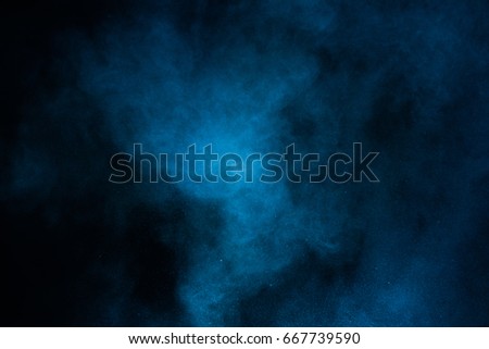 Freeze motion of blue powder exploding, isolated on black, dark background. Abstract design of white dust cloud. Particles explosion screen saver, wallpaper with copy space. Planet creation concept   