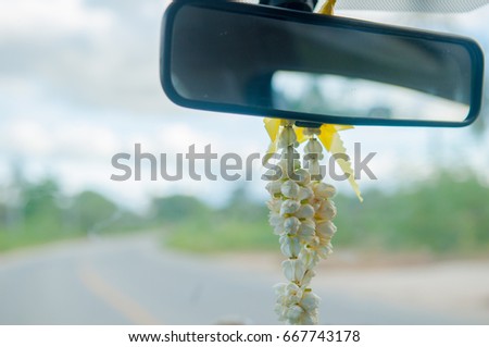 Jasmine wreath hanging on rear view mirror in car in Thailand .Almost Thai people believe about spirit in machine .And using flower to pray for spirit of vehicle.