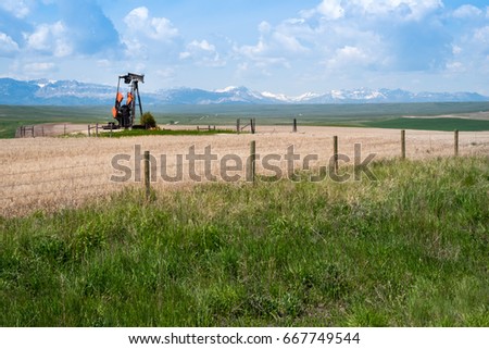 Natural Gas Pump Jack in Field with Mountain Backdrop

