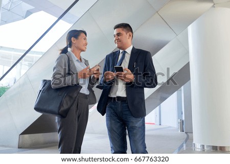 Cheerful multi-ethnic coworkers standing in modern office and talking