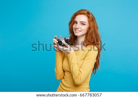 Close up Portrait young beautiful attractive ginger girl happy smiling with vintage camera and ready to travel. Blue Pastel Background. Copy space.