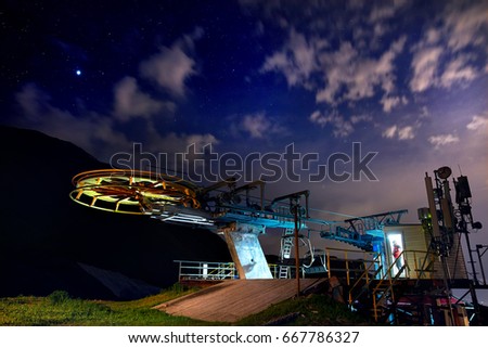 Cable car station with Lifeguard in red jacket in the door of building at the mountain ski resort with starry night sky 
