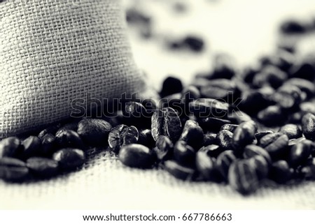 Coffee bean and burlap bag on wooden table blur background dark tone colors