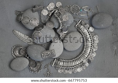 Bohemian style silver jewelry set and pebble on vintage grey background. Top view point.