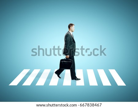 Side view of man wth briefcase walking on crosswalk. Blue background