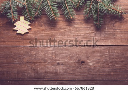 Gingerbread homemade cookies with icing and christmas tree branch on a wooden table or board for background. New year theme. Toned.
