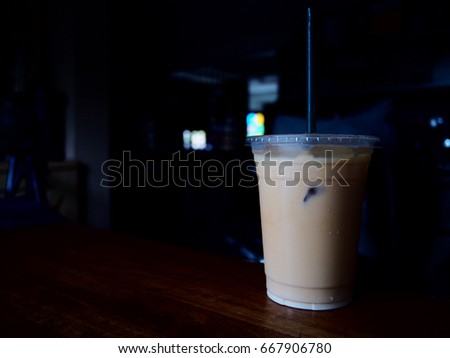 It's time for tea. The picture of iced Thai tea in plastic cup above wooden table. dark background.  soft tone