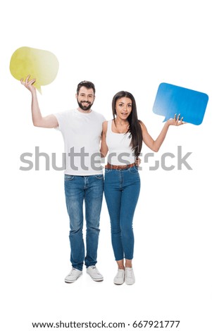Smiling couple holding blank speech bubbles isolated on white