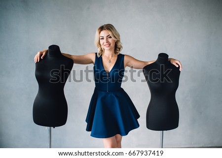 Woman fashion designer stands near the mannequins