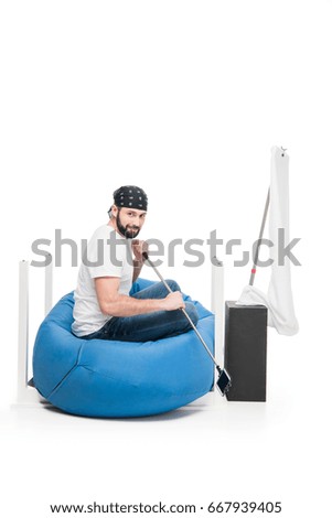 side view of man sitting on bag chair and pretending being pirate isolated on white