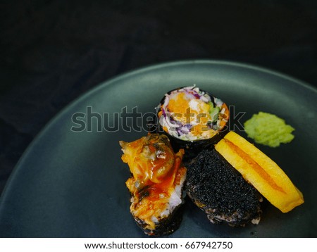Colorful sushi on black plate.