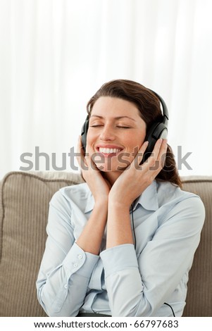 Cheerful businesswoman listening music on the sofa at home