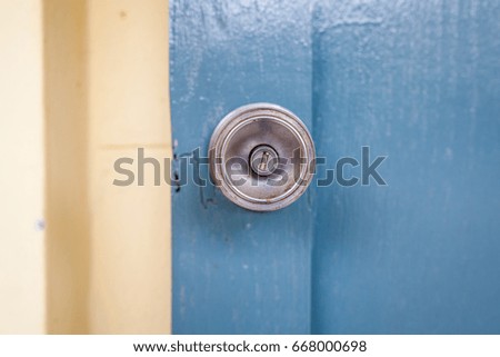 Door handle with blue wooden door and yellow wall