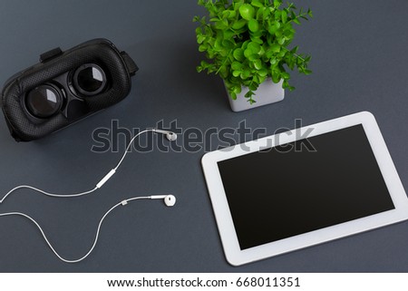 Virtual reality glasses and tablet with headphones on a gray background. Top view
