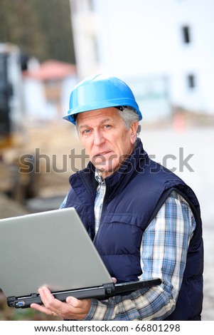 Architect with drawing on construction site