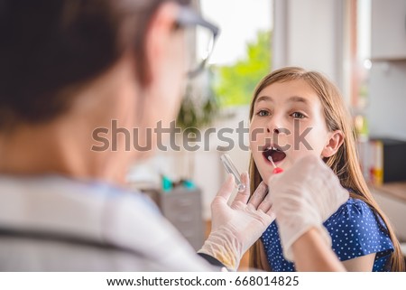 Female pediatrician using a swab to take a sample from a patient's throat Royalty-Free Stock Photo #668014825