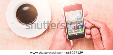 Illustration of various video and icons against hands holding smartphone next to cup of coffee