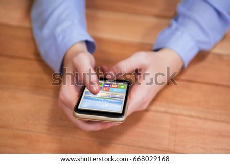 Graphic image of various video and icons against businesswoman text messaging while holding mobile phone