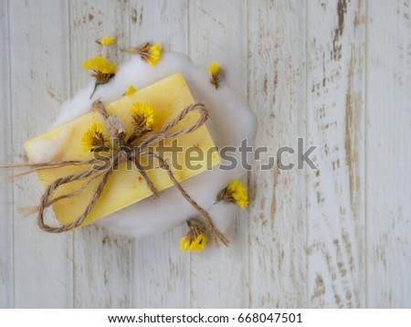Yellow herbal soap, bubble, dried yellow wildflowers on white wooden vintage background