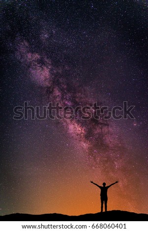 Landscape with Milky way galaxy. Night sky with stars and silhouette happy man on the mountain. Long exposure photograph.