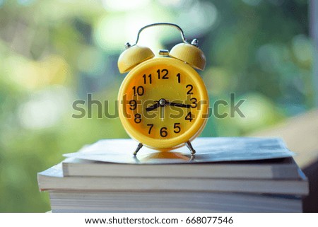 Yellow Alarm clock on books nature background