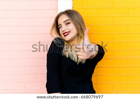 Happy woman with thumb up. Bright brick background. Modern concept of business and success.
