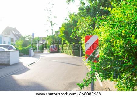A beautiful sunny street with a road sign and gardens. 