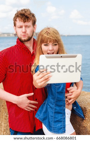 Technology holidays and happiness concept. Young couple taking self picture selfie with tablet outdoor on by seaside