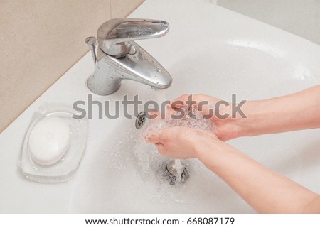 woman washing hands with soap in bathroom