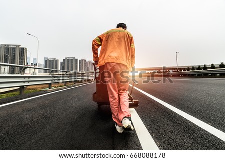 On the highway transport workers to the road cross the white solid lines

