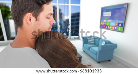 Rear view of couple embracing against blue sofas in living room at modern house