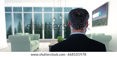 Businessman pretending to standing against invisible screen against blue sofas on floor in modern living room