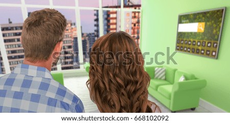 Rear view of young couple standing against composite image of modern living room