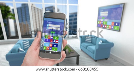 Hand holding mobile phone against white background against blue sofas in living room at modern house