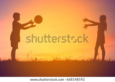Silhouette, happy children playing ball on meadow, sunset, summertime