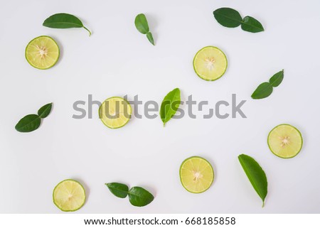 Sliced lime and lime leaves laid into the background. Royalty-Free Stock Photo #668185858