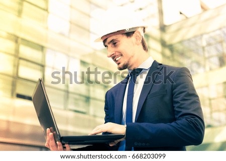 Portrait of cheerful man builder talking about work at the laptop outdoors