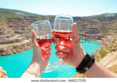 hands hold to clink glasses with glasses with penguins on sea background. view. romance. love