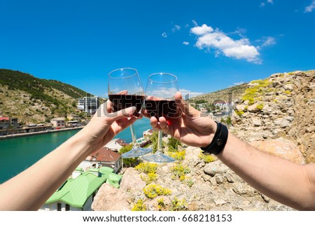 hands hold to clink glasses with glasses with penguins on sea background. view. romance. love