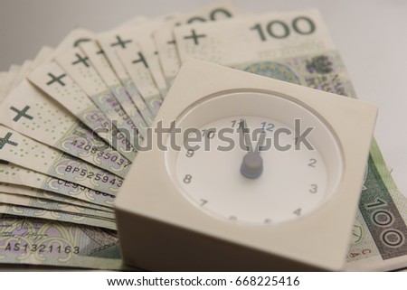 Close-up of clock and money with silver background, stack of Polish Zloty banknotes (PLN)